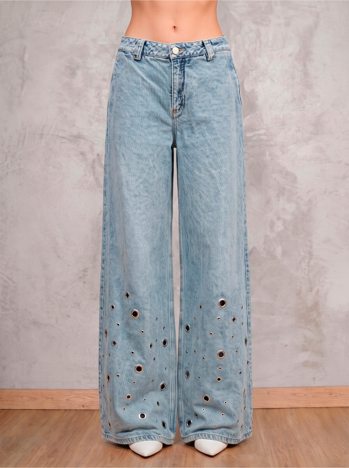 Detalle frontal del jean azul claro wide leg Arya de DAVD, aplicaciones tipo ojal sobre denim azul claro.