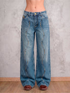 Detalle frontal del jean azul medio wide leg Azurite de DAVD, aplicaciones metálicas en tono bronce sobre denim azul medio.